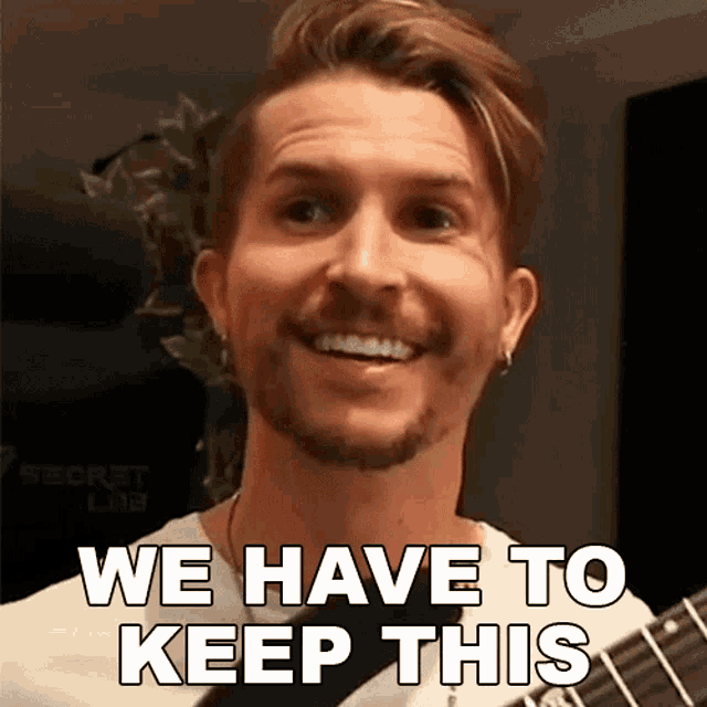 a man holding a guitar with the words we have to keep this on his face