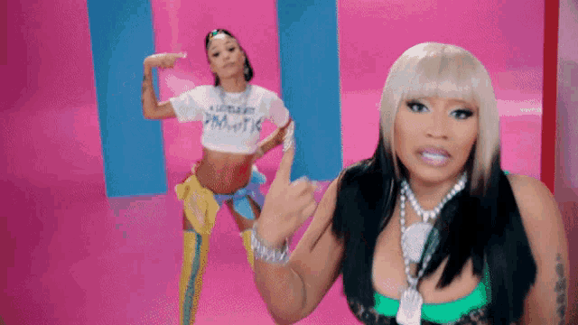 a woman wearing a shirt that says ' nicki minaj ' on it stands next to another woman