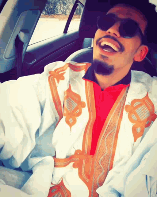 a man wearing sunglasses and a white jacket is laughing