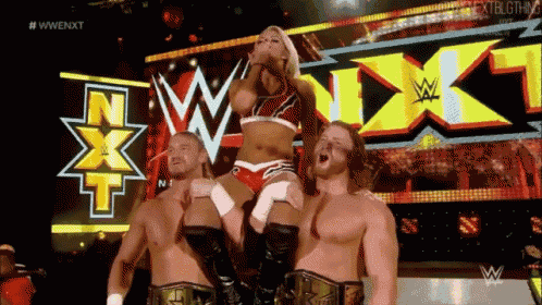 a female wrestler is being lifted by two male wrestlers in front of a sign that says nxt