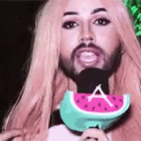 a man with a beard is holding a microphone and a watermelon slice .