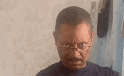 a man with glasses and a beard is making a funny face in front of a mirror .