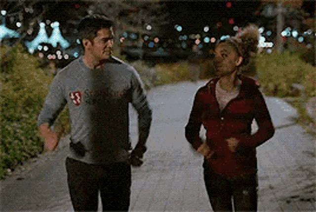 a man and a woman are running down a sidewalk .