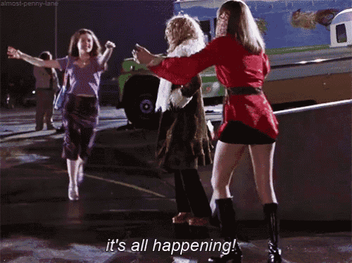three women are dancing in a parking lot and one of them is saying it 's all happening !