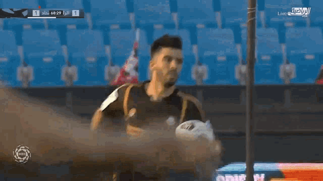 a soccer player is holding a soccer ball in front of a scoreboard with the number 1 on it