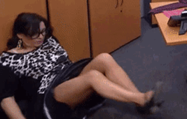 a woman in a leopard print dress is laying on a chair with her legs crossed