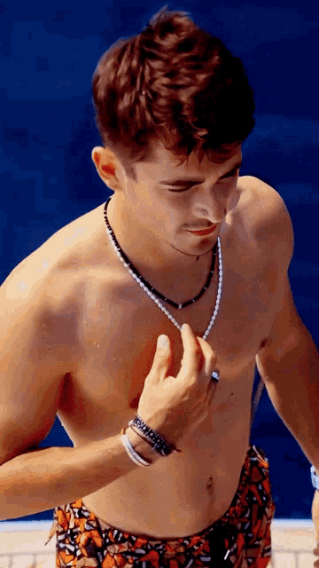 a shirtless man is wearing a pearl necklace and bracelets