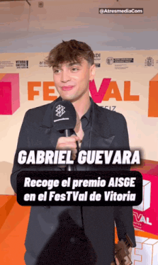 gabriel guevara is standing in front of a sign that says festival on it