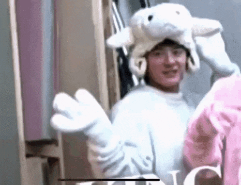 a man wearing a sheep hat and gloves is standing next to a woman .