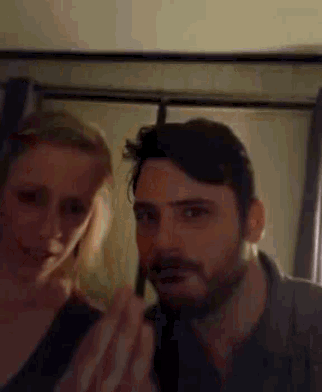 a man and a woman are standing next to each other and the woman is applying makeup to the man 's face .