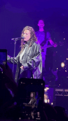 a woman singing into a microphone on a stage in a dark room