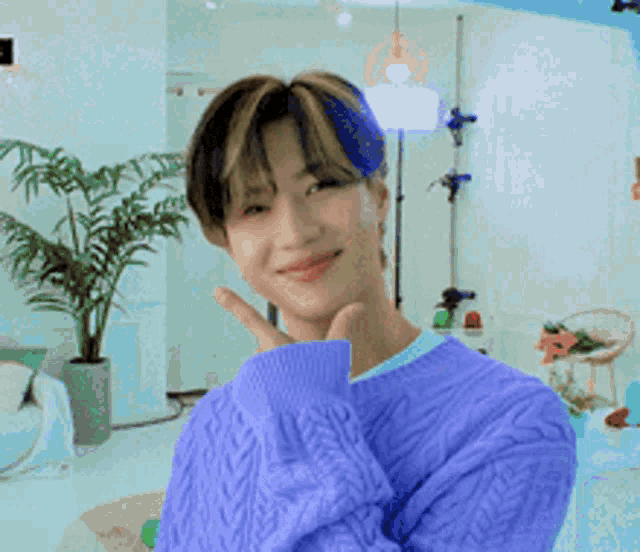 a young man in a blue sweater is giving a peace sign .