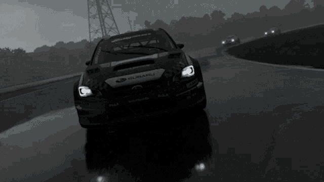 a subaru is driving down a wet road in the rain