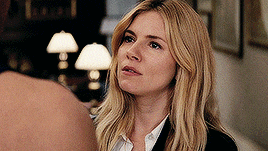 a woman with blonde hair and a black jacket is looking at a man 's back