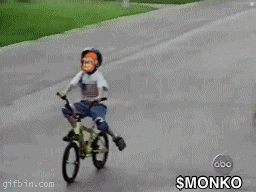a young boy wearing a helmet is riding a bike with a monkey face on it