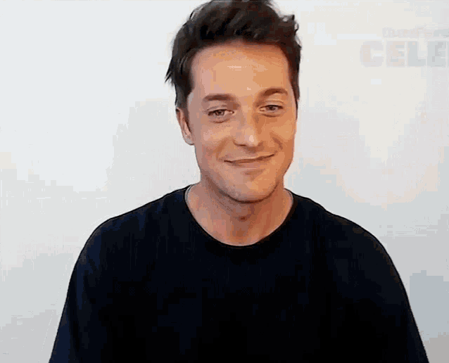 a man in a black shirt is smiling and looking at the camera