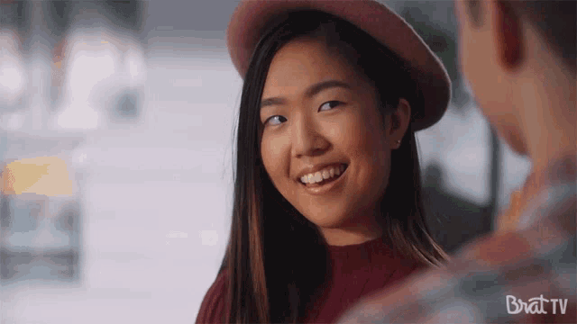 a woman wearing a pink hat is smiling at a man with brattv written in the corner