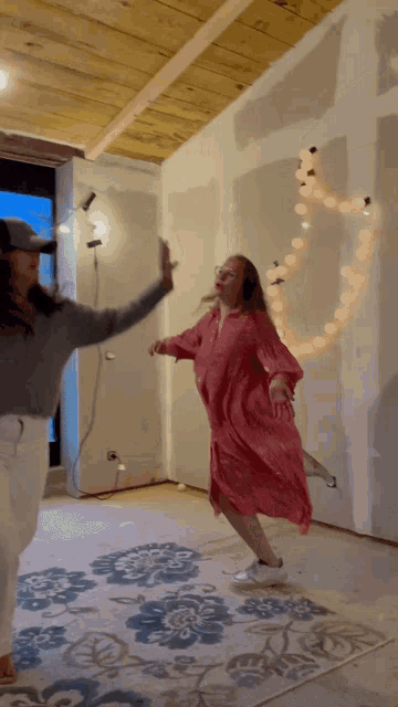 a woman in a pink dress is dancing with another woman in a room