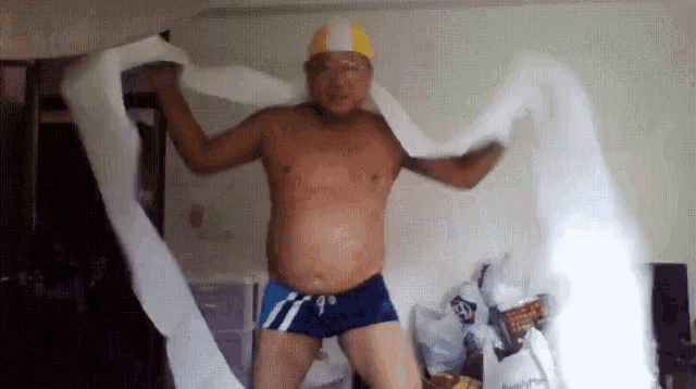 a shirtless man wearing a swim cap is holding a roll of toilet paper