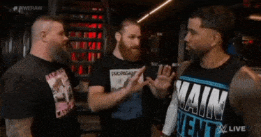 a group of men are standing next to each other in a room talking to each other .