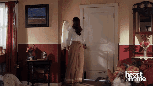 a woman standing in a room with a super channel logo on the bottom
