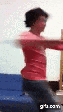 a person in a red shirt is dancing on a blue couch ..