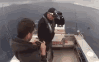 a man is taking a picture of another man on a boat in the water .