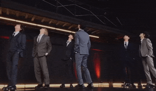 a group of men in suits and ties are dancing