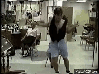 a man is dancing in a hair salon with a woman sitting in a chair .