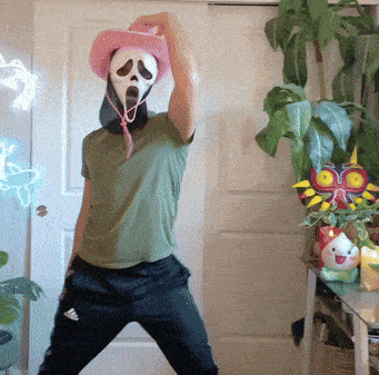 a man wearing a scream mask and a pink hat