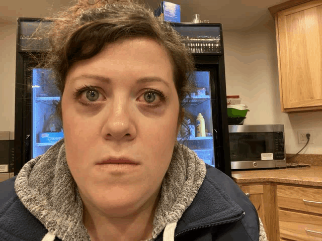 a woman 's face is shown in front of a refrigerator that has a blue box on it