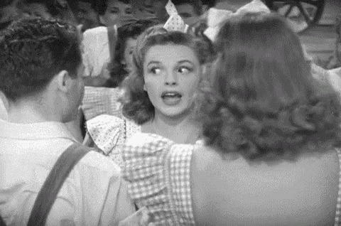 a black and white photo of a woman in a party hat talking to a man .