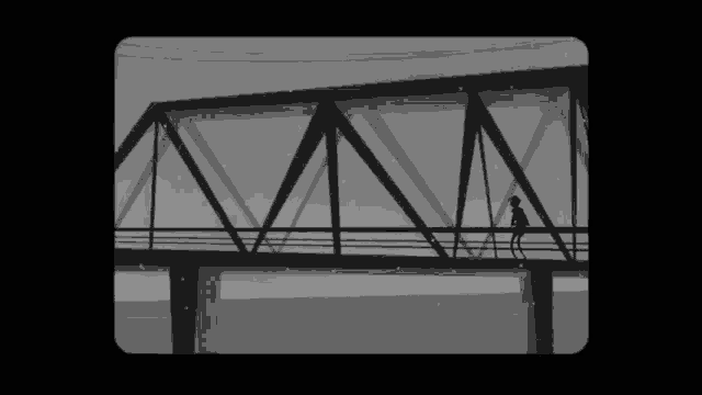 a silhouette of a person walking across a bridge