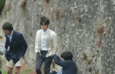 a group of people are standing next to each other in front of a wall .