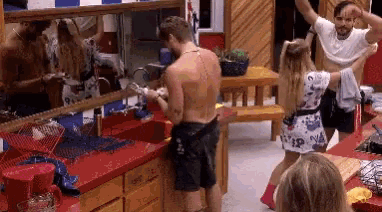 a man and a woman are dancing in a kitchen while a woman looks on .