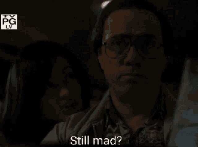 a man and a woman are watching a movie and the man is saying still mad
