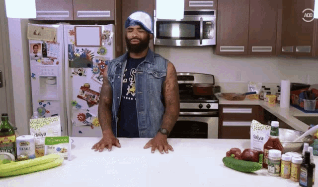 a man standing in a kitchen wearing a shirt that says s on it