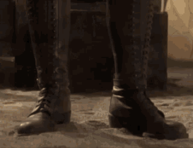 a close up of a person 's feet wearing boots on a sandy surface .
