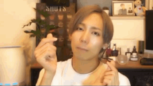 a man in a white shirt is making a heart with his hands .