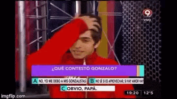 a man in a red jacket holds his hand to his head in front of a screen that says qué contesto gonzalo .
