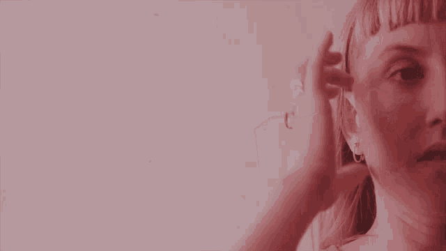 a close up of a woman 's face with a hand touching her hair