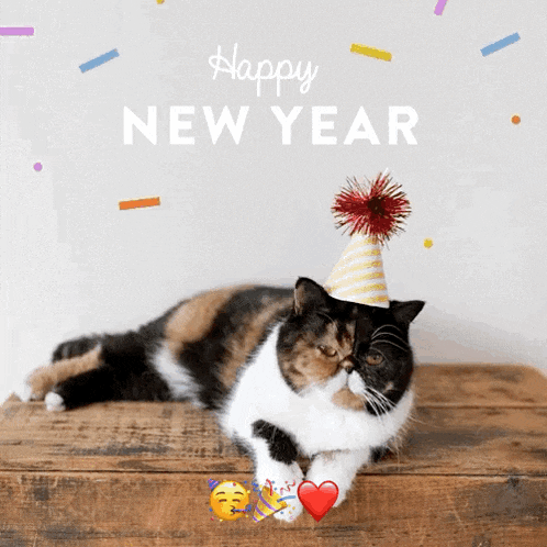 a calico cat wearing a party hat laying on a wooden table with the words happy new year written above it