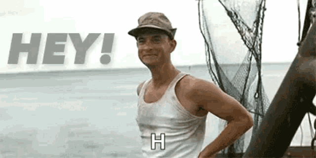 a man wearing a hat and a tank top is standing in front of a body of water .