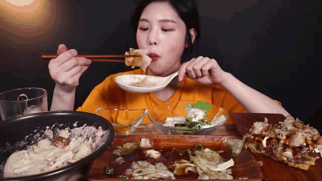 a woman eating a salad with chopsticks and a spoon