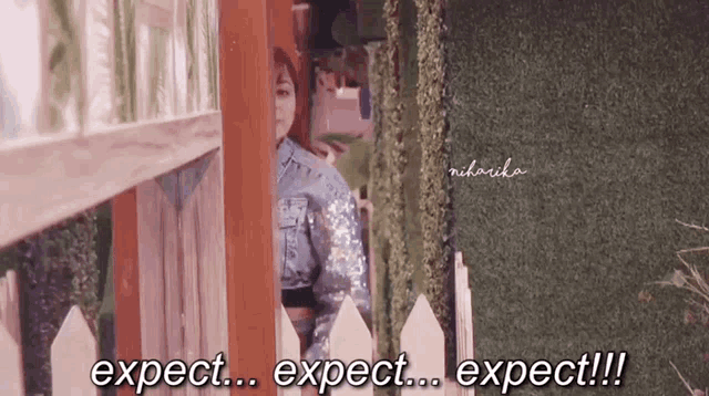 a woman standing behind a fence says expect expect expect