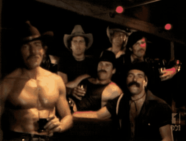 a group of men wearing cowboy hats are standing in a dark room