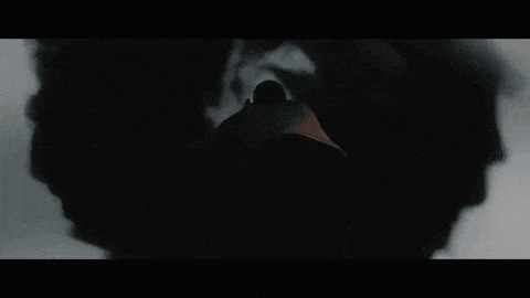 a man is standing in a dark room surrounded by black smoke .