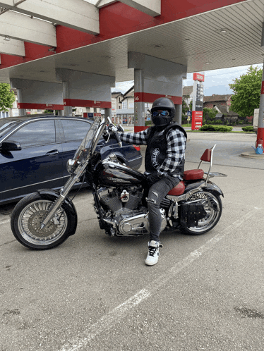 a man on a harley davidson motorcycle in front of a gas station