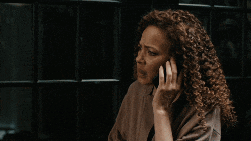 a woman with curly hair is talking on a cellphone
