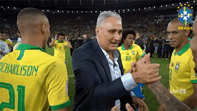 a man in a suit is shaking hands with a soccer player wearing a shirt that says charlison on it